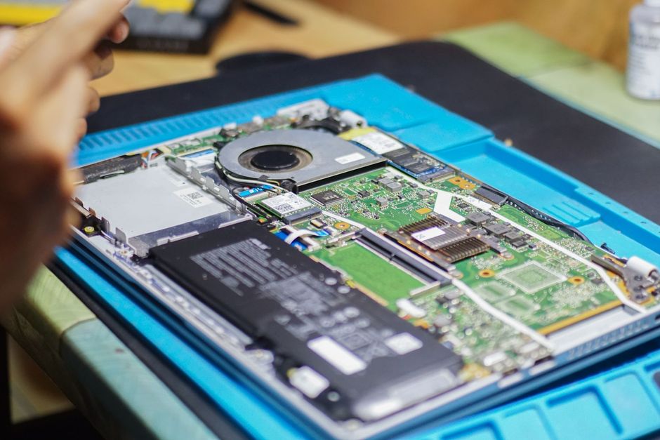 Technician repairing an open laptop on a workbench